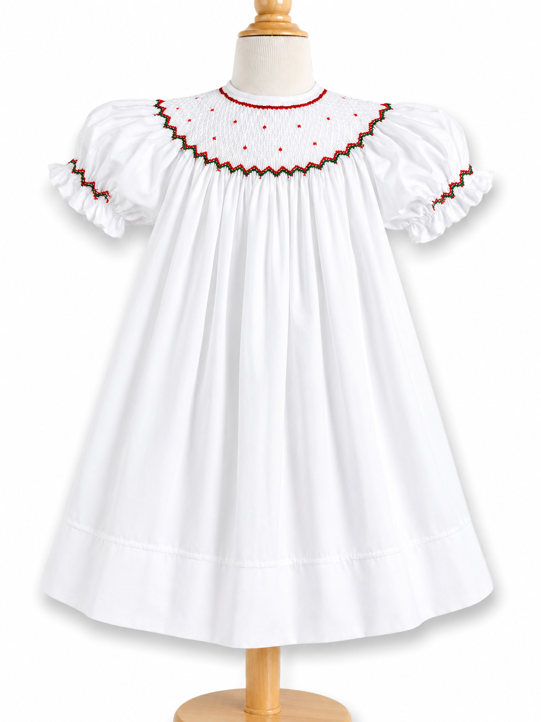 This dress features short puff sleeves, a smocked yoke with red tiny bullion flowers around the neck and red/green embroidered trim.  An additional wrapped around smocked on the sleeves