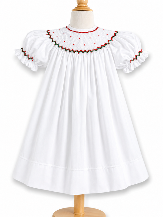 This dress features short puff sleeves, a smocked yoke with red tiny bullion flowers around the neck and red/green embroidered trim.  An additional wrapped around smocked on the sleeves